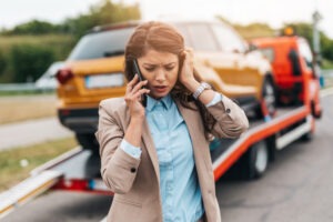 A woman on the phone in front of her car being towed. How long do truck accident cases take to settle in Texas?