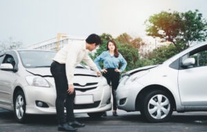 A man and a woman having a conversation in front of a car accident. How long does it take to settle a car accident case in Texas?
